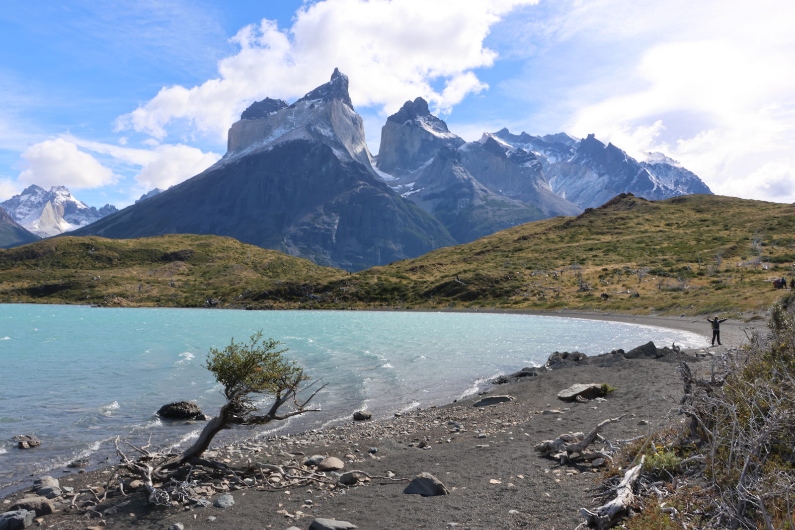 The Cuernos del Paine and surrounding peaks rising above turquoise waters and rolling hills in Torres del Paine National Park, Chile.