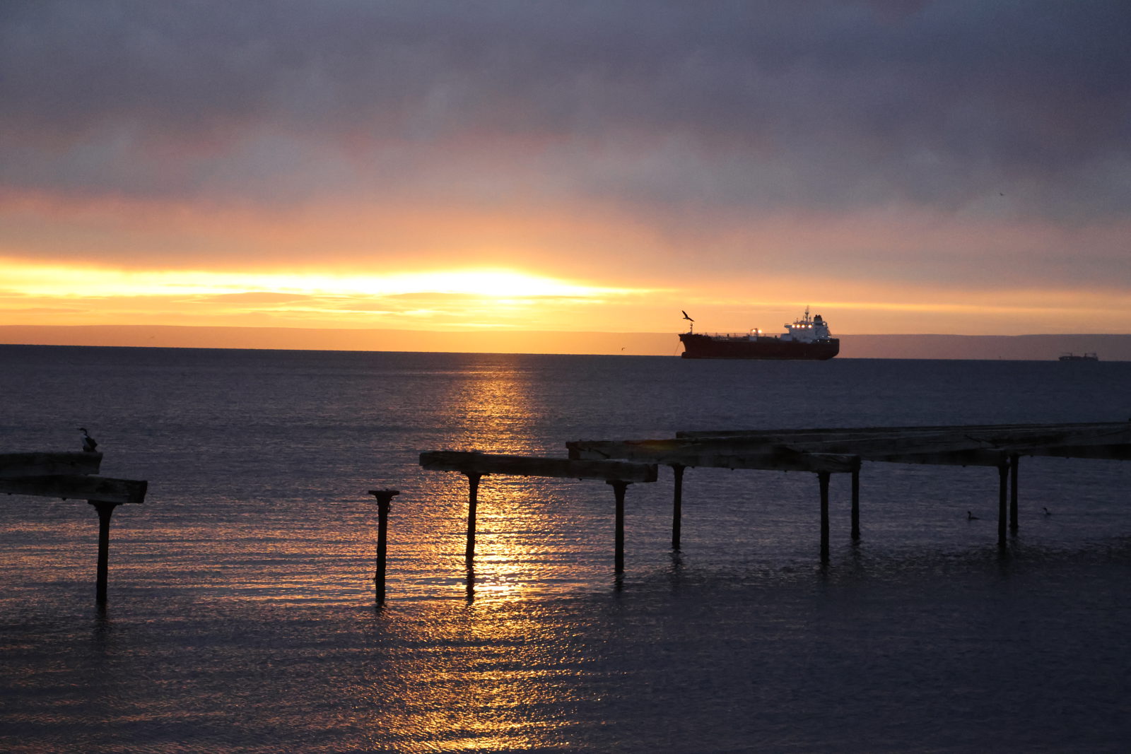 Sunset over the Strait of Magellan with a cargo ship off Punta Arenas, Chile.