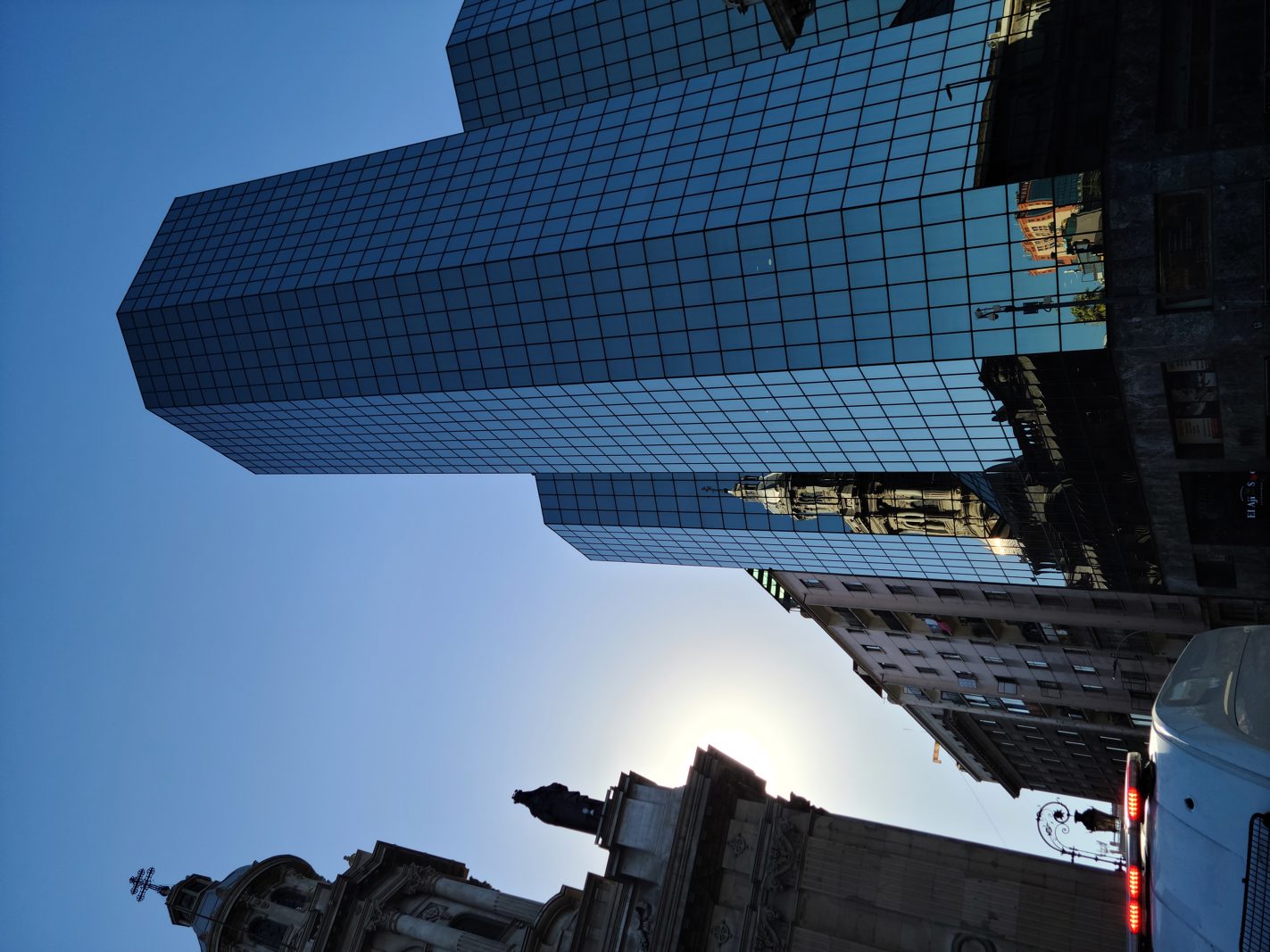 Modern glass skyscraper reflecting historic buildings in downtown Santiago, Chile.