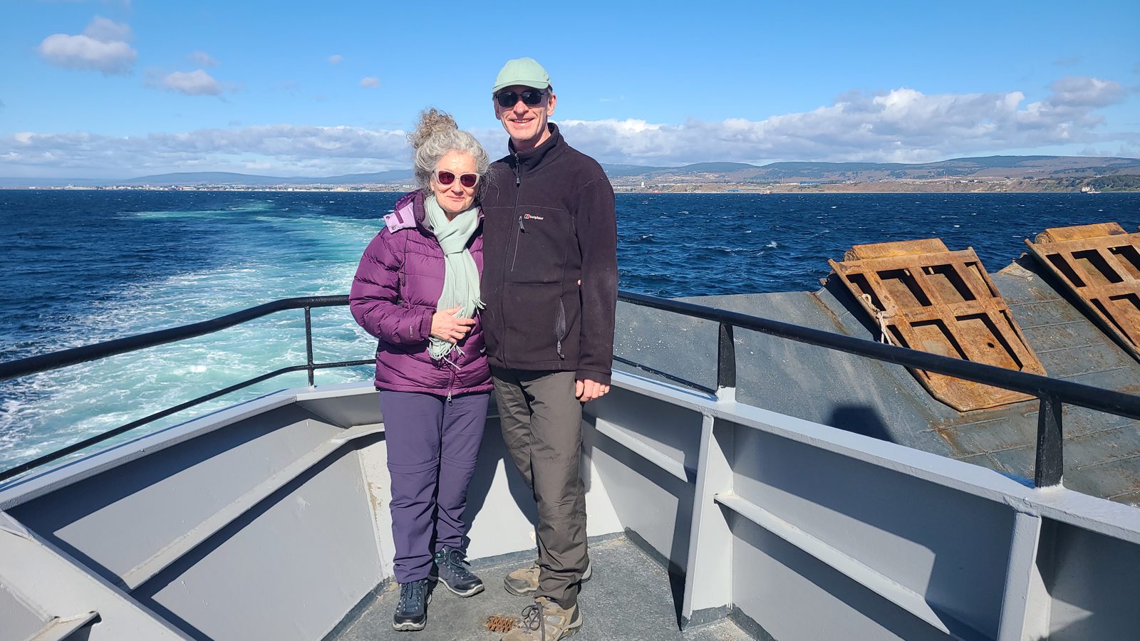 Couple standing on the open deck of a ferry crossing the Strait of Magellan from Punta Arenas to Isla Magdalena.