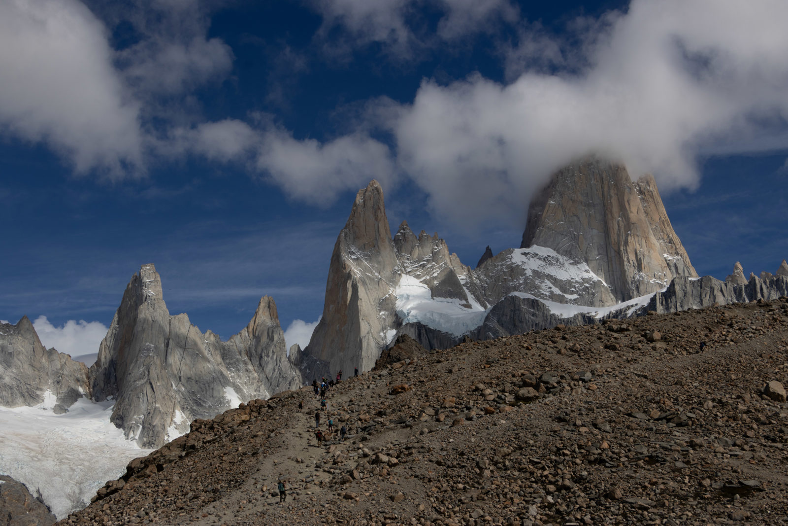 Hikers approaching the final ridge below the granite towers of Fitz Roy near Laguna de los Tres in Patagonia.