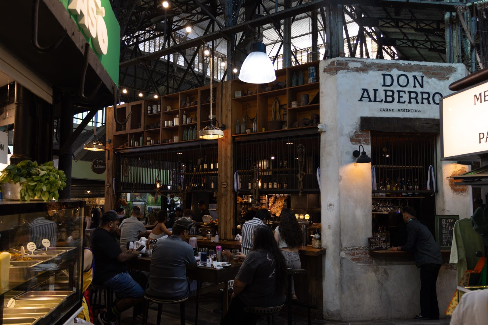 Don Alberto café inside Mercado de San Telmo in Buenos Aires, with diners enjoying food beneath the market's historic iron roof.