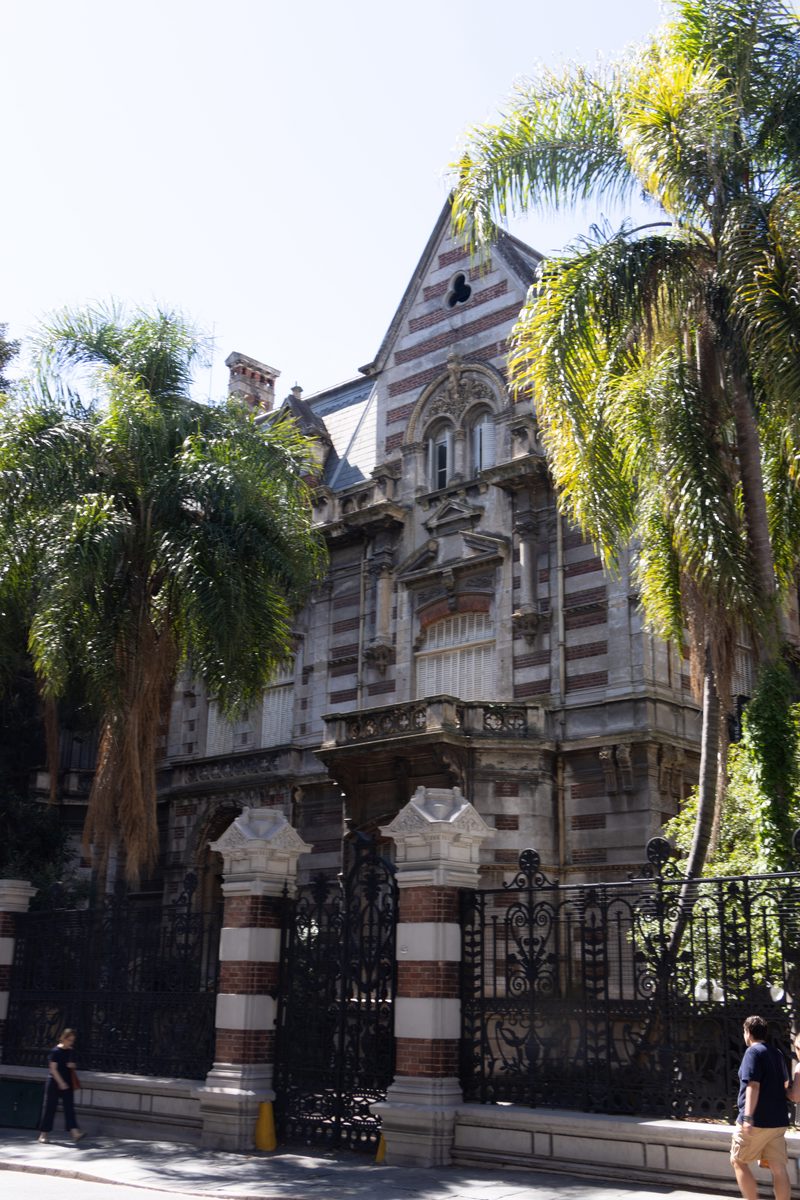 Historic mansion on Avenida Alvear in Buenos Aires, featuring ornate European-style architecture, palm trees and decorative wrought-iron gates