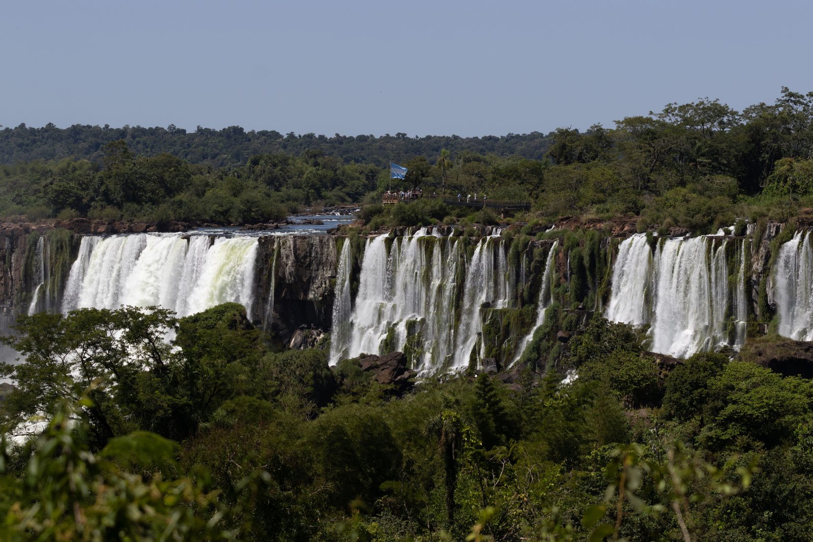 Panoramic view of the horseshoe-shaped Iguazú Falls with multiple waterfalls cascading through the rainforest.