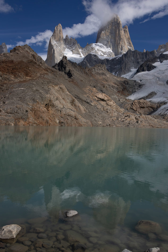 Reflection of the Fitz Roy granite towers and clouds in the turquoise water of Laguna de los Tres in Patagonia.