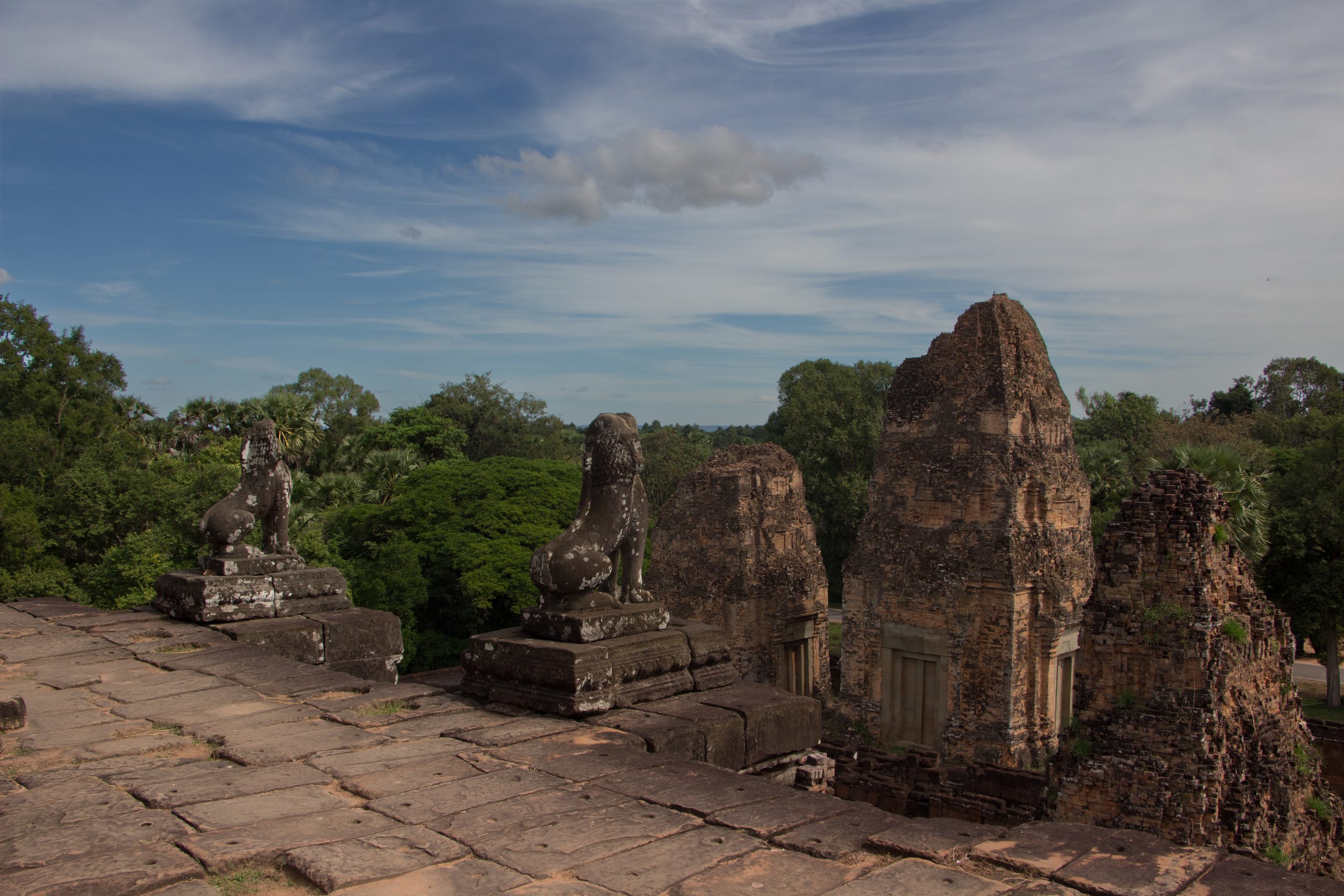 View across the upper terrace of Pre Rup with guardian figures and brick towers rising above the surrounding trees.