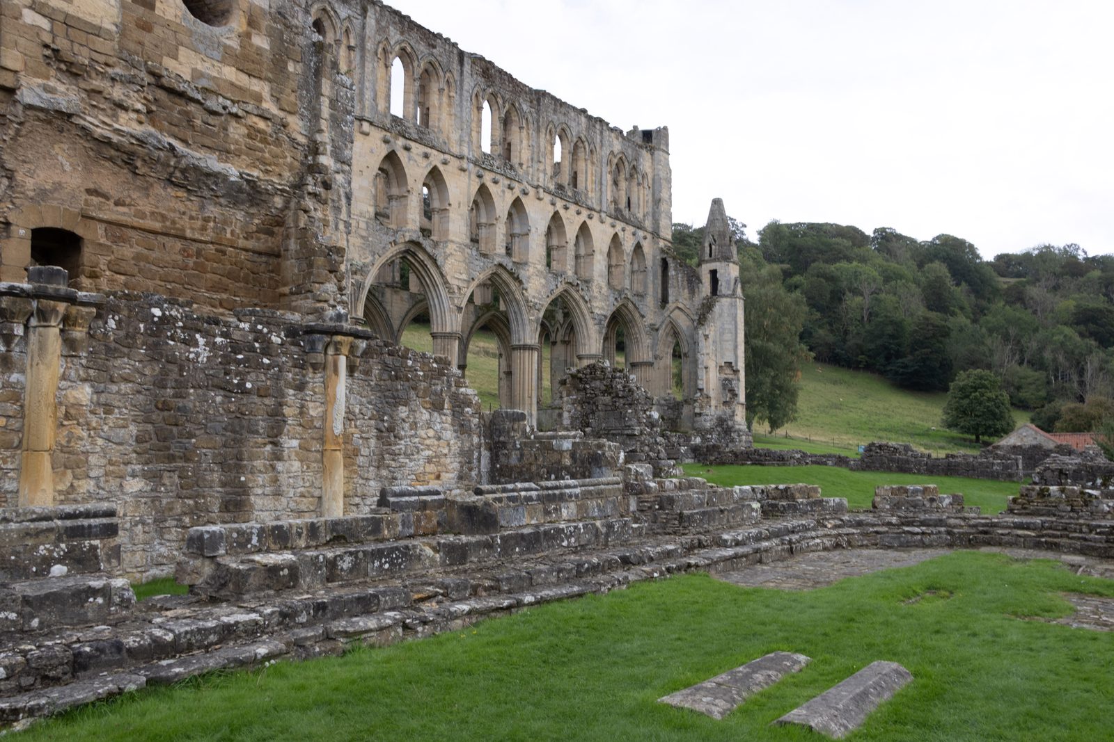 Side view of a long stone wall with arches at Rievaulx Abbey