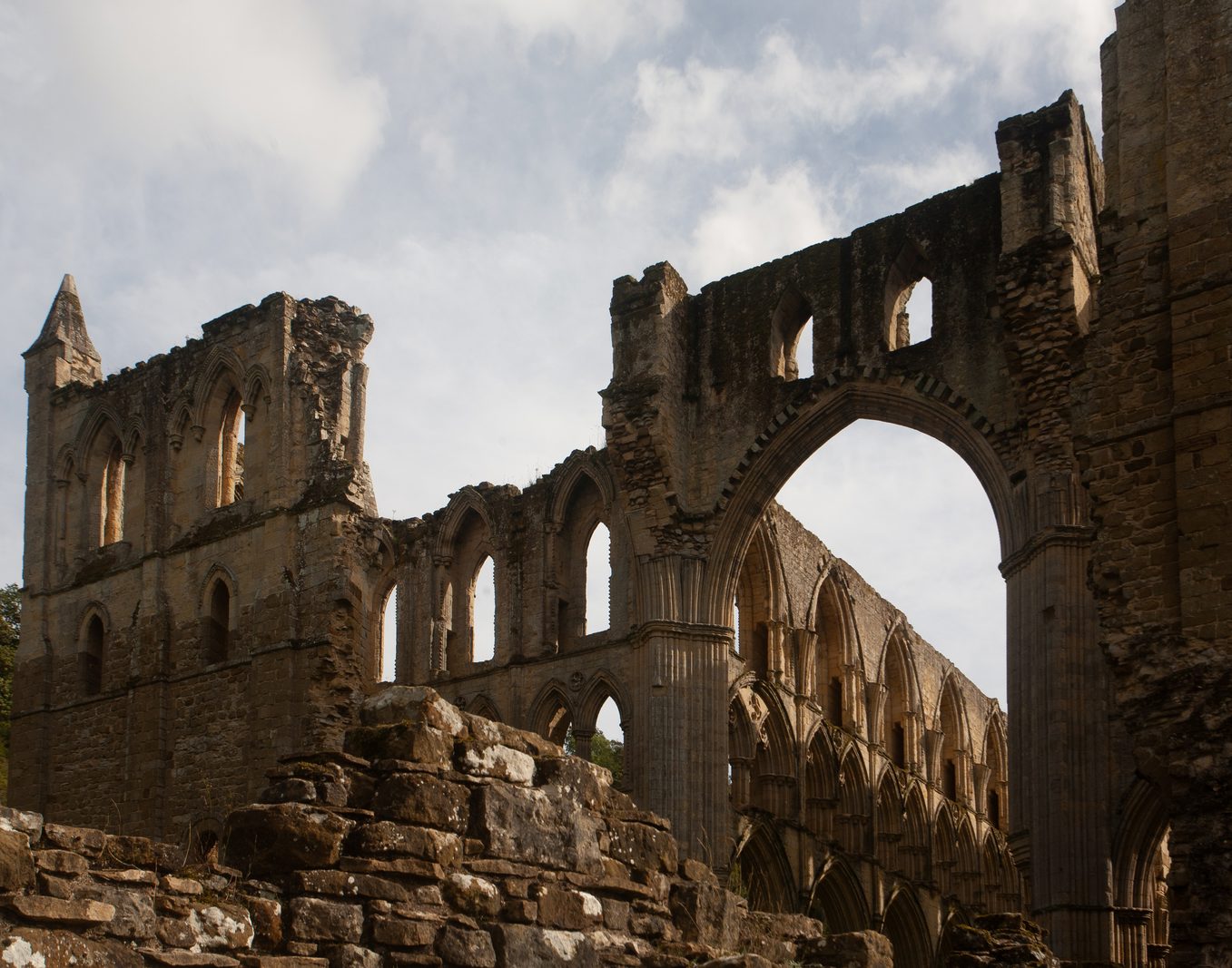 Broken stone walls and a large arch at Rievaulx Abbey