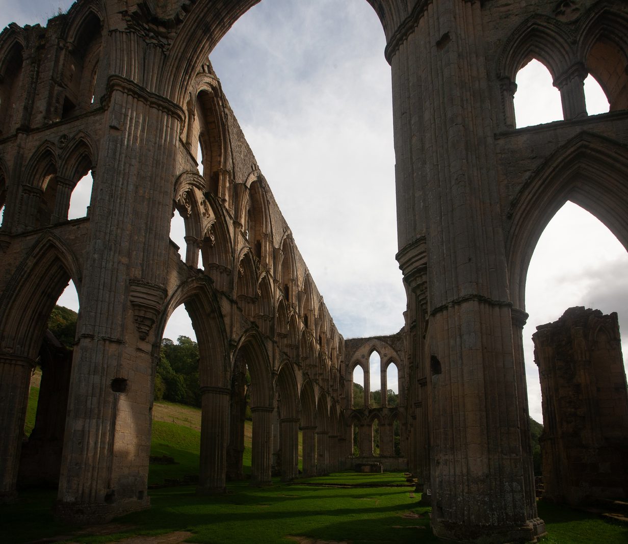 Roofless abbey interior seen between tall stone columns and arches